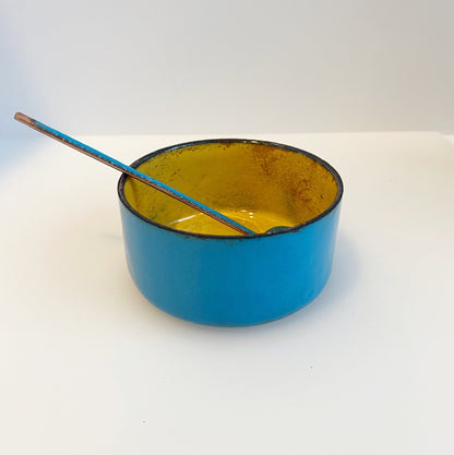 copper pot enamelled in teal on the outside, yellow on the inside with teal spoon